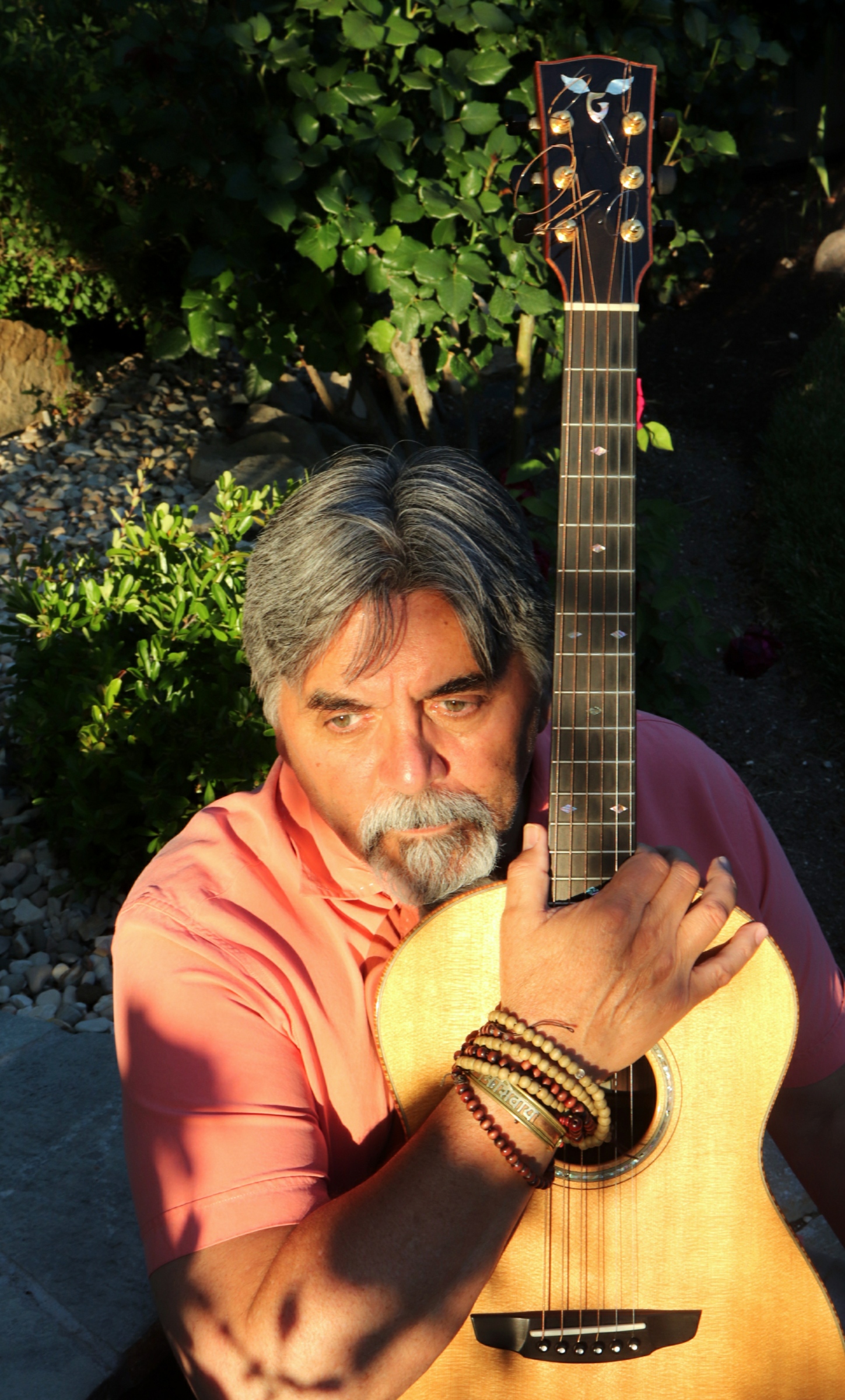 Mark in apricot colored shirt holding vertical guitar